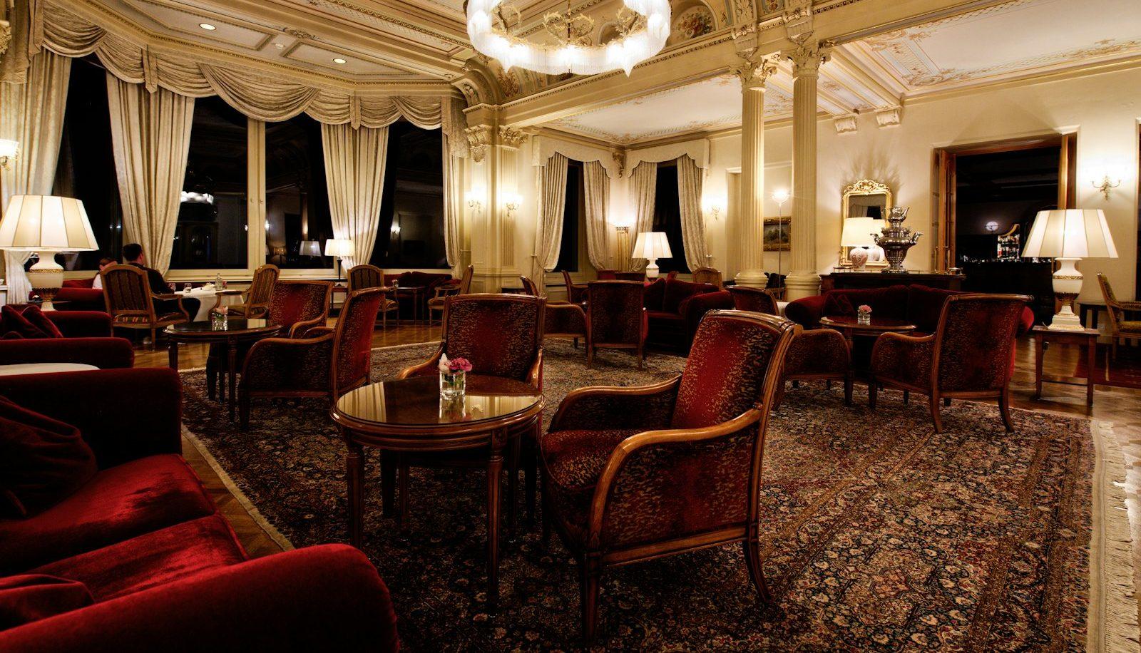 Patterned rug beneath red velvet armchairs in a formal hotel lounge