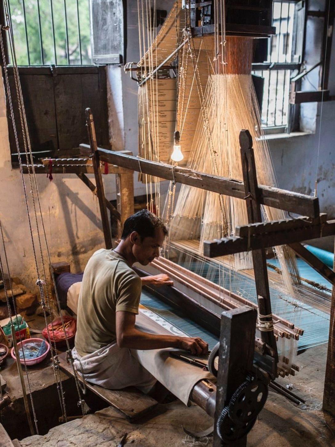 Artisan working warp threads by hand in the workshop